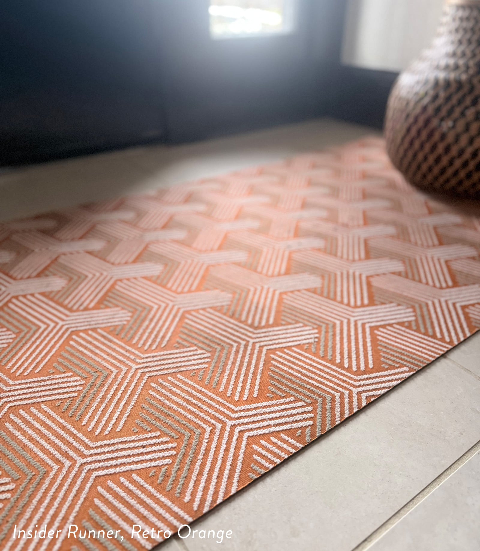 Geometric patterned rug on a wooden floor with a blurred background